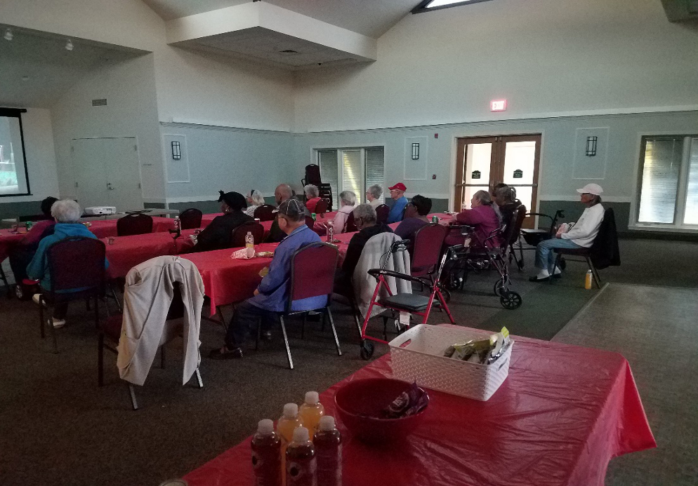 A group of people sitting at tables with red tablecloths.