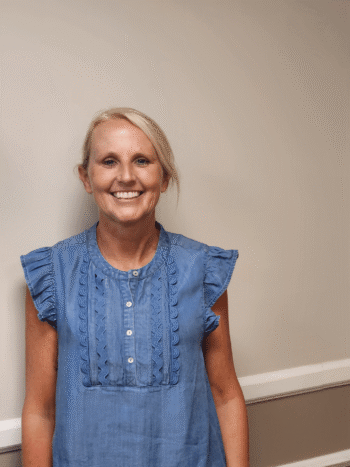 Smiling woman in blue ruffled blouse.