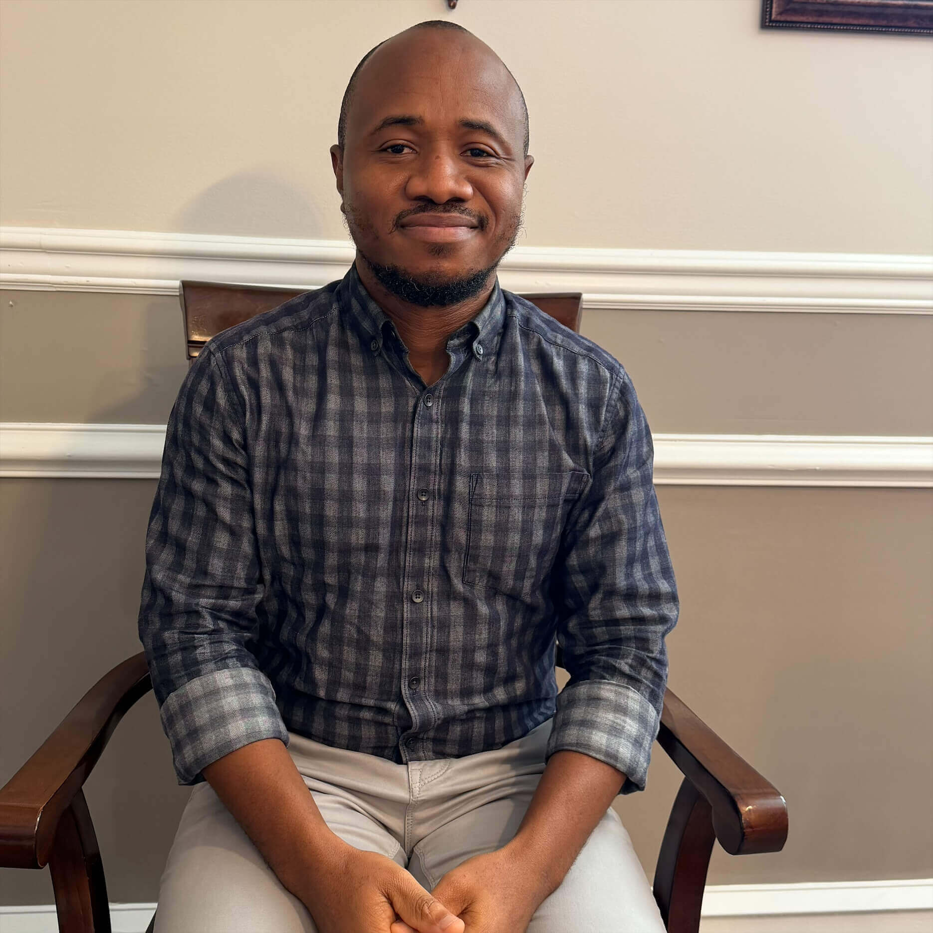 Man sitting on chair, smiling, indoors.
