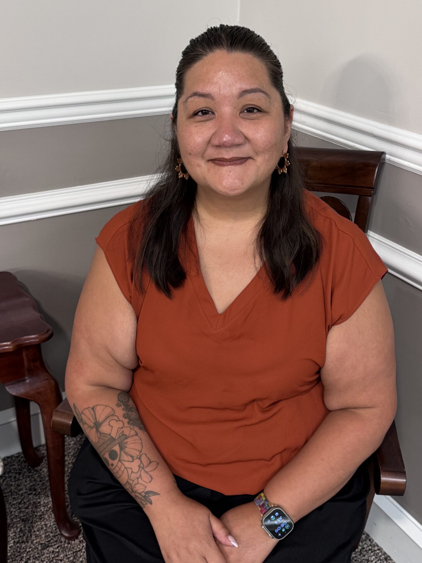 Smiling woman with forearm tattoo in orange shirt